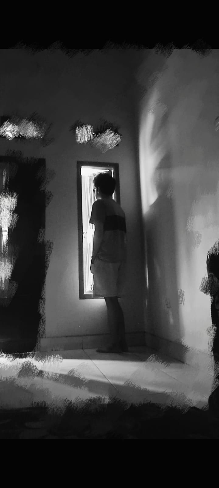 potret seorang pria yang sedang memandang dunia luar dari jendala panjang rumahnya